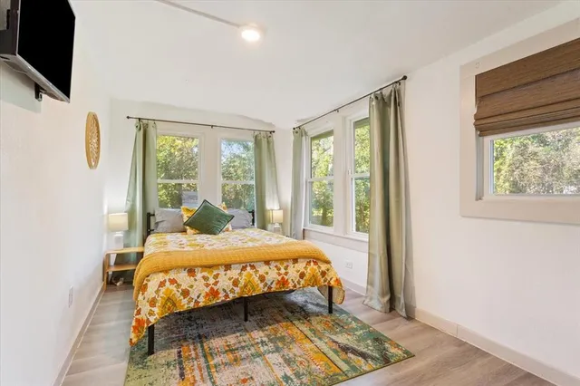 a bedroom with a bed a flat screen tv and next to a window
