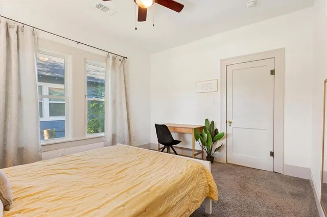 a bedroom with a bed a window and potted plant on a dresser