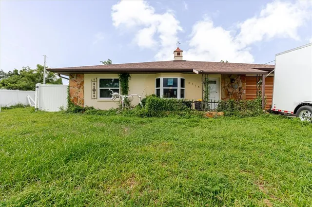 a front view of house with yard and trees in the background