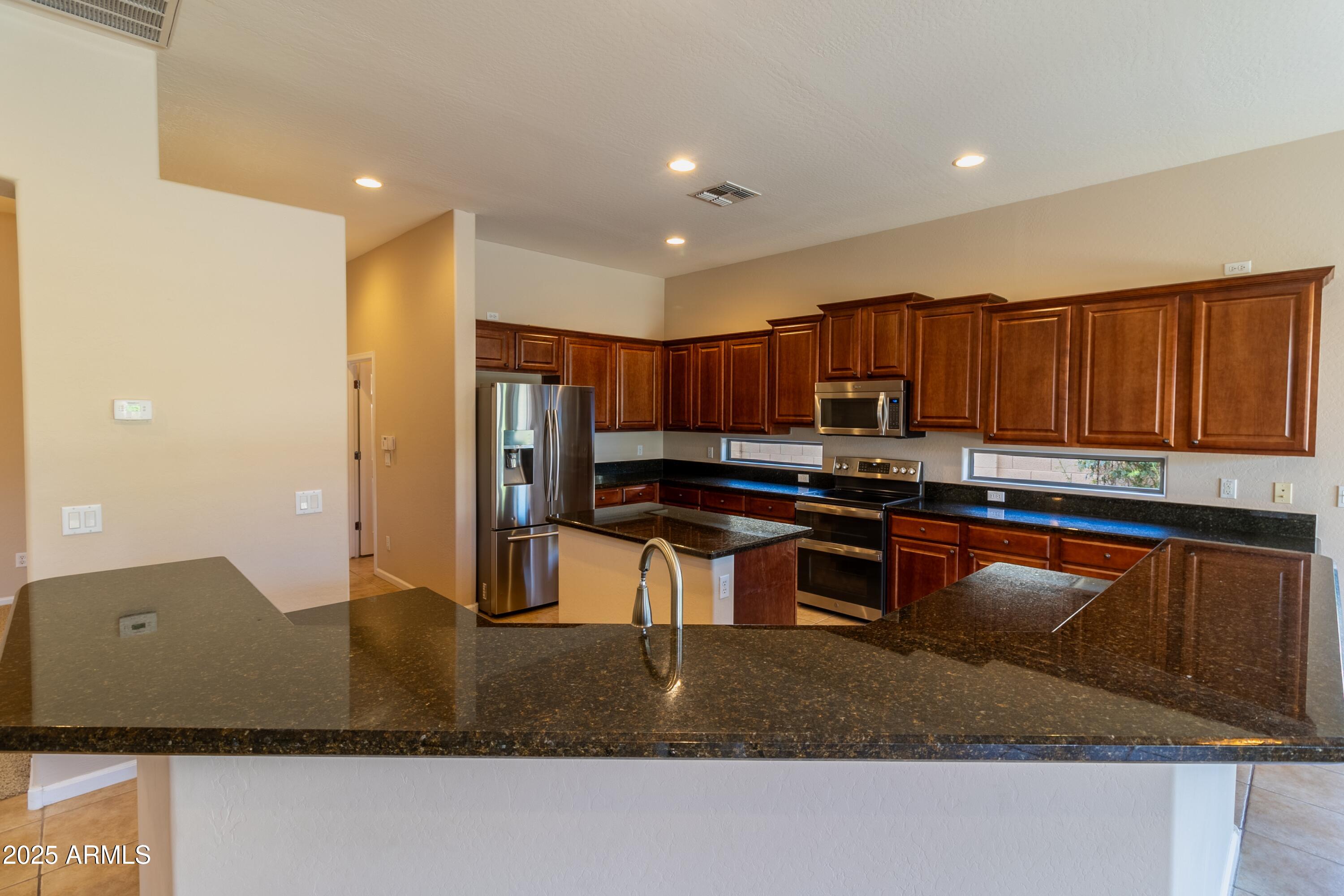 4241 East Andre Avenue Gilbert, AZ 85298 - Photo 8 of 39 a kitchen with stainless steel appliances granite countertop a refrigerator a stove a sink and a counter space