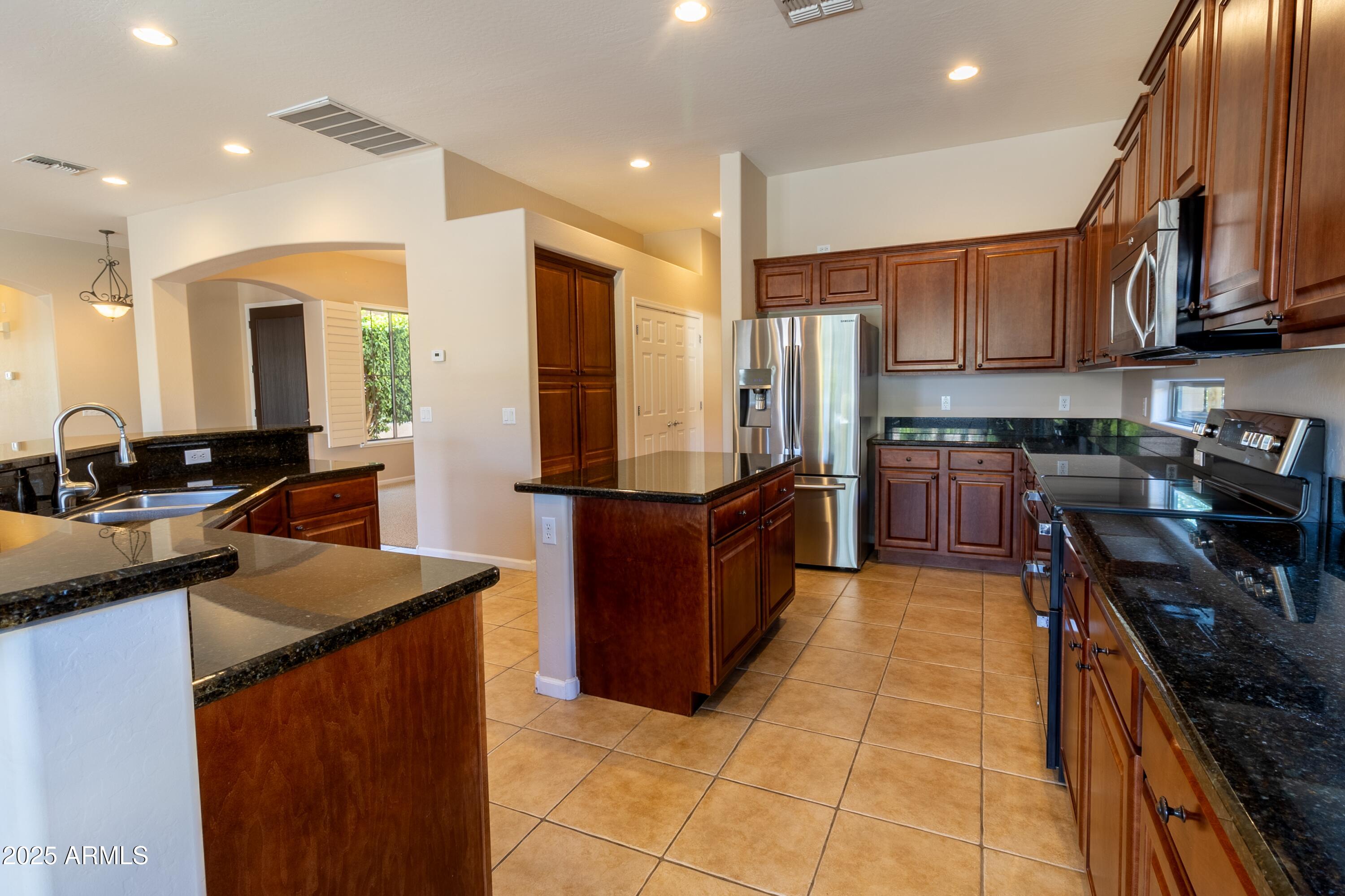 4241 East Andre Avenue Gilbert, AZ 85298 - Photo 10 of 39 a kitchen with stainless steel appliances granite countertop wooden cabinets a sink dishwasher a stove and a refrigerator