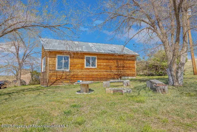 a backyard of a house with large trees and wooden fence