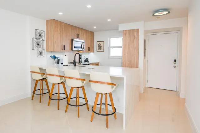 a kitchen with stainless steel appliances kitchen island granite countertop a table chairs and a refrigerator