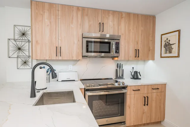 a kitchen with stainless steel appliances granite countertop a stove a sink and a microwave