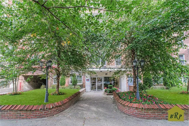 a front view of a house with a garden and tree