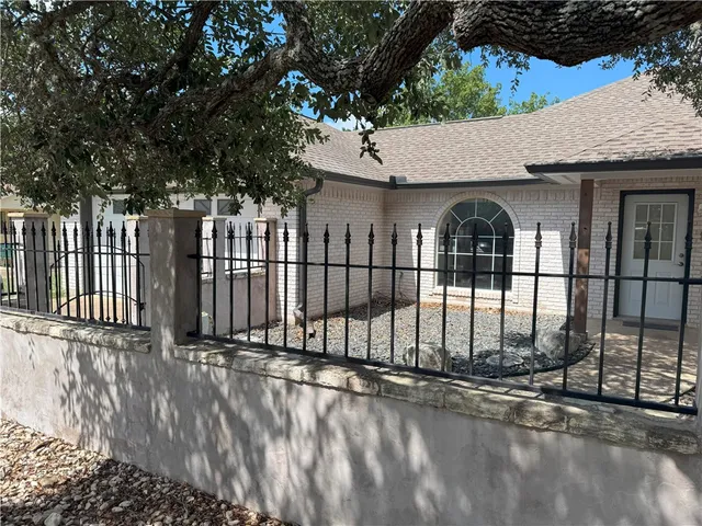 a backyard of a house with large trees and wooden fence