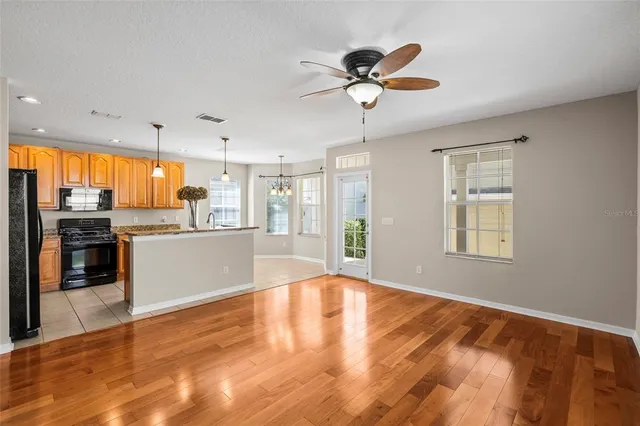 a kitchen with stainless steel appliances granite countertop a refrigerator a sink dishwasher a stove and white cabinets with wooden floor