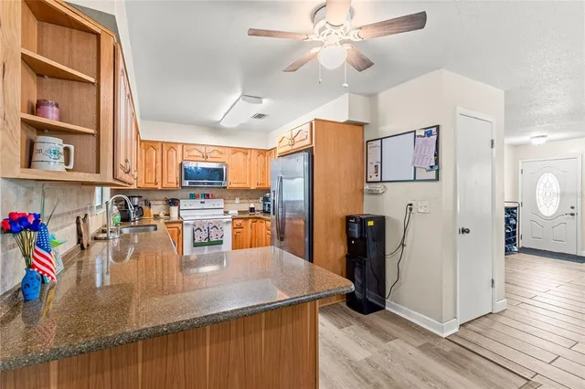 a kitchen with stainless steel appliances granite countertop a refrigerator a stove and a sink with cabinets