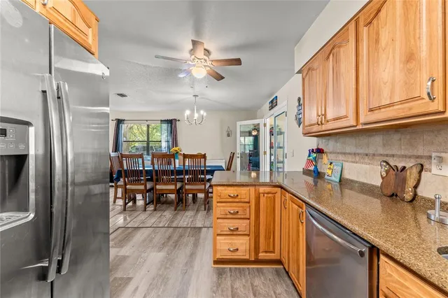 a kitchen with stainless steel appliances granite countertop a refrigerator a sink dishwasher a stove and white countertops with wooden floor