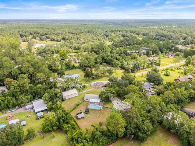 an aerial view of residential houses with outdoor space and trees