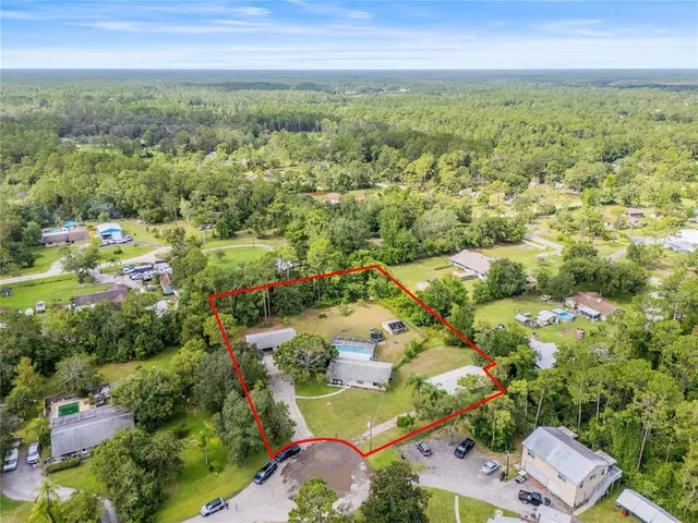 an aerial view of residential houses with outdoor space and trees