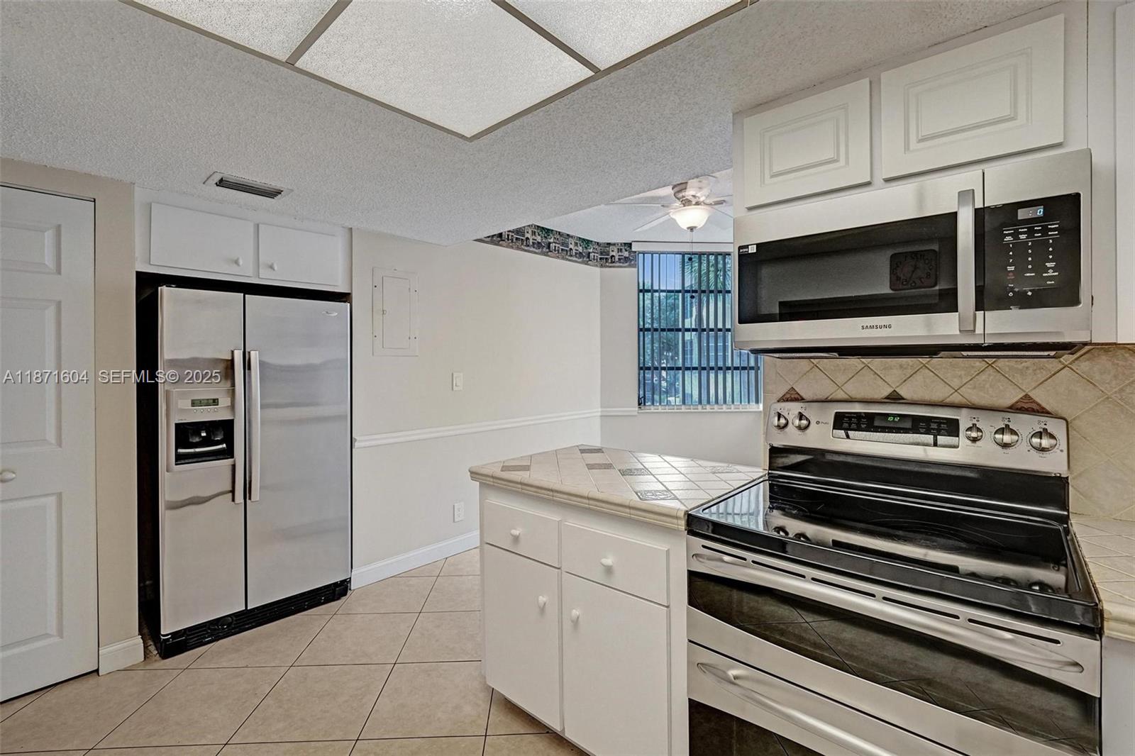 1900 Sabal Palm Drive, Unit 201 Davie, FL 33324 - Photo 10 of 23 a kitchen with stainless steel appliances kitchen island granite countertop a stove and a microwave