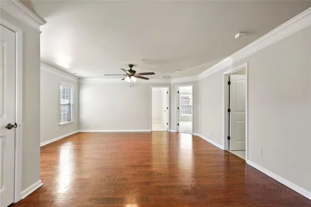 a view of an empty room with a window and wooden floor