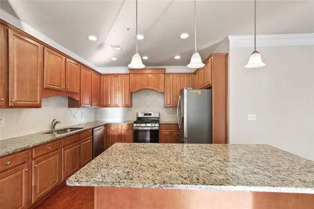 a kitchen with stainless steel appliances granite countertop a sink refrigerator and cabinets
