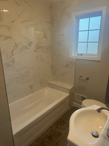 a bath tub sitting next to a white sink and a toilet