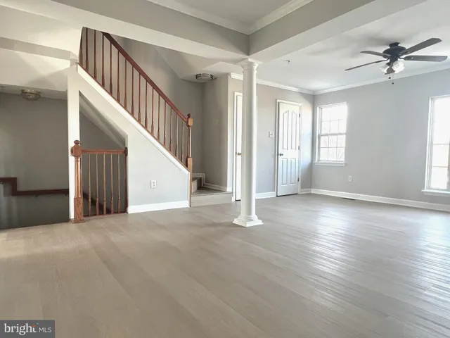 a view of an empty room with wooden floor and a ceiling fan
