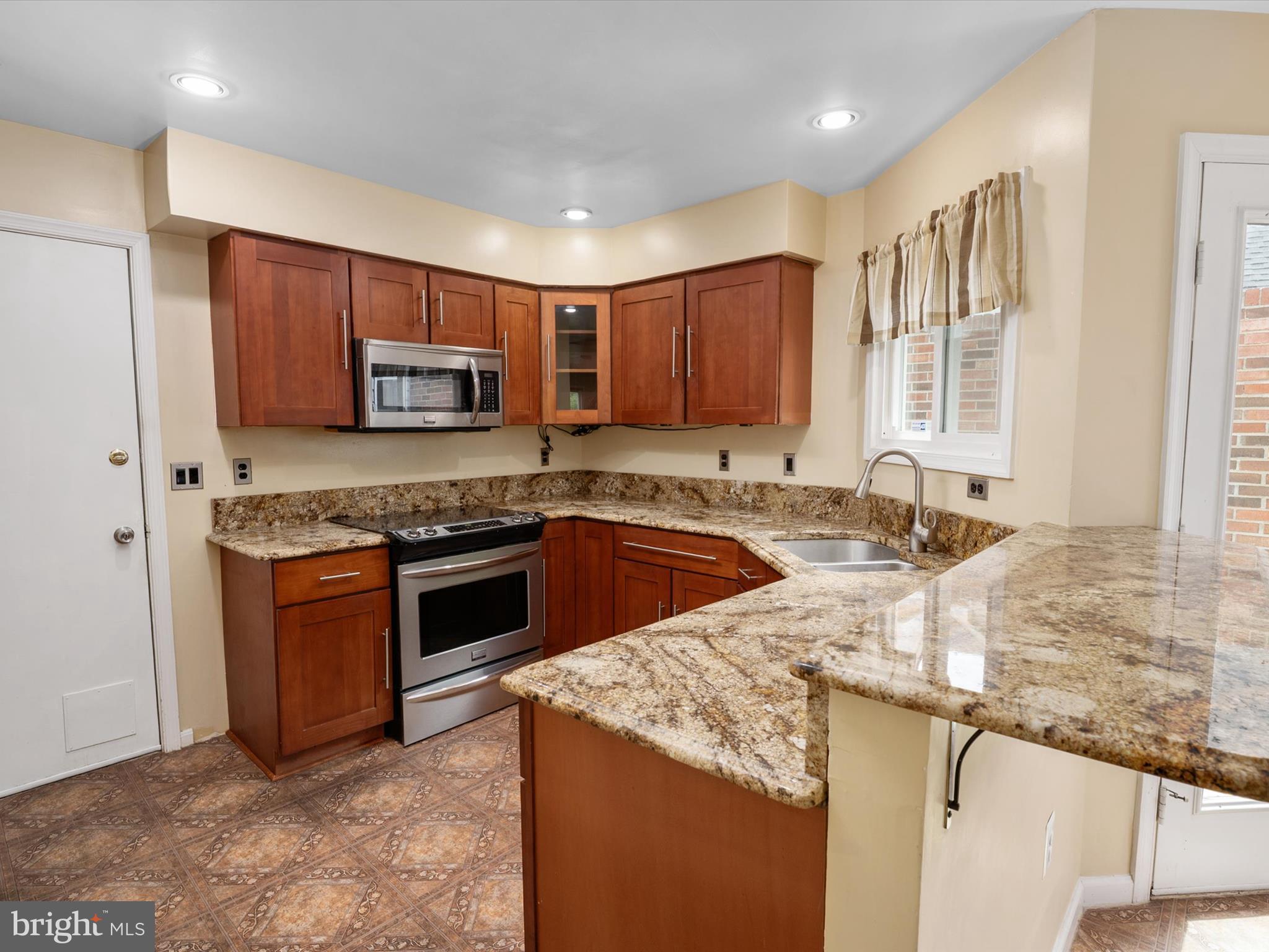14226 Greenview Drive Laurel, MD 20708 - Photo 19 of 46 a kitchen with stainless steel appliances granite countertop a stove a sink and a microwave