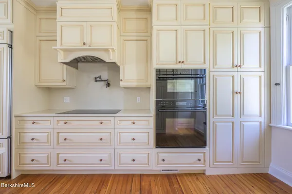 a kitchen with stainless steel appliances white cabinets and wooden floors