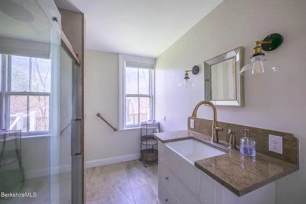 a view of a hallway with wooden floor and a bathroom