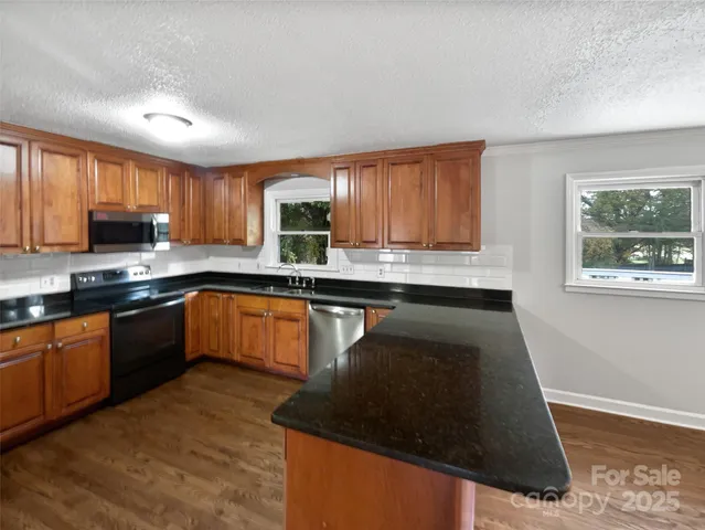 a kitchen with granite countertop a stove a sink and a microwave