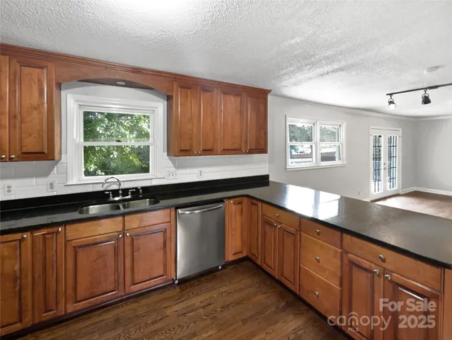 a kitchen with stainless steel appliances granite countertop wooden cabinets a sink and dishwasher with wooden floor