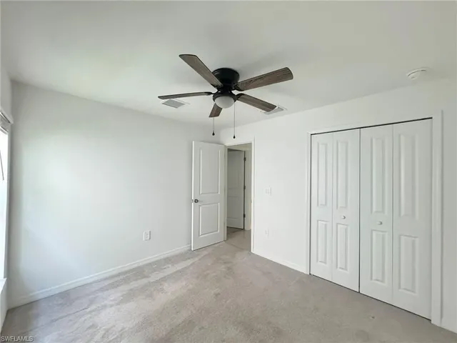 an empty room with a ceiling fan and a window