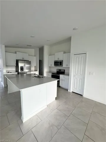 a large kitchen with kitchen island granite countertop a stove a sink a counter top space and cabinets