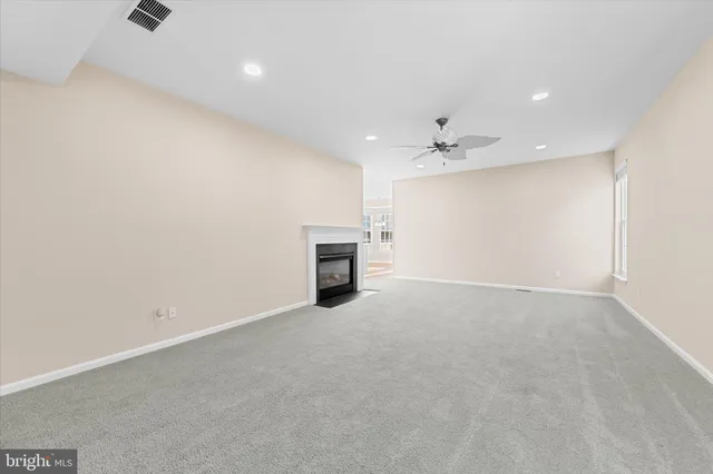 an empty room with a ceiling fan and a fireplace