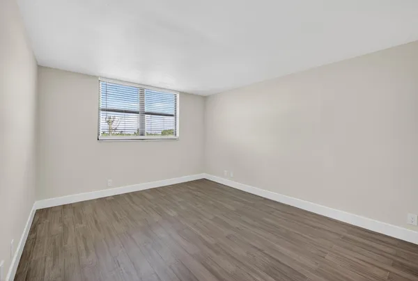 a view of an empty room with wooden floor and white doors