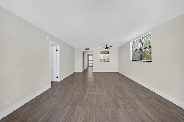 an empty room with wooden floor and windows