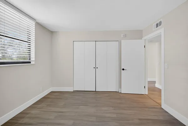 a view of a hallway with wooden floor and closet