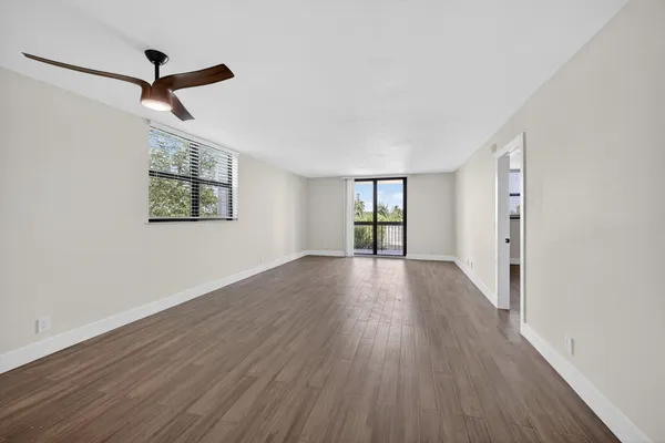 a view of empty room with wooden floor and fan