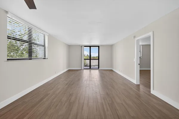 a view of an empty room with wooden floor and a window