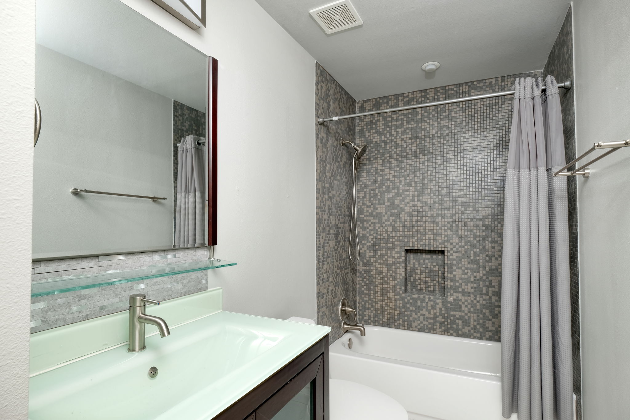 3000 Speedway Street, Unit E Austin, TX 78705 - Photo 10 of 16 Modern bath features a vibrant mosaic tiled shower and an elegant glass vanity with a sleek faucet.