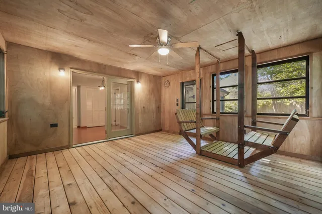 a view of empty room with wooden floor and fan