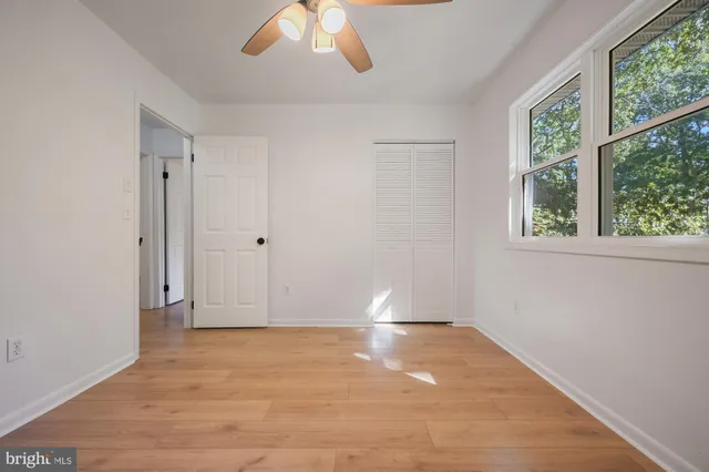 a view of empty room with wooden floor and fan