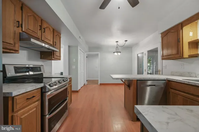 a kitchen with stainless steel appliances granite countertop a sink a stove and a wooden floors