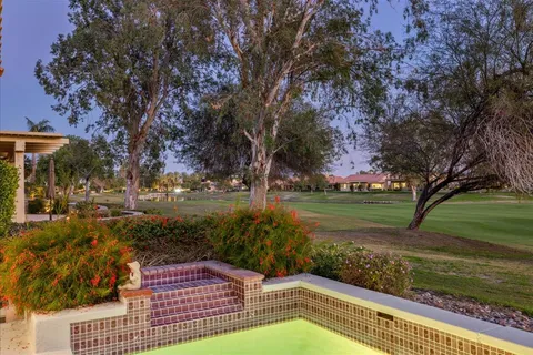 a view of a big house with a big yard a fountain and a large tree