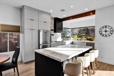 a kitchen with stainless steel appliances granite countertop a dining table chairs and a refrigerator