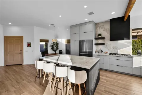 a kitchen with stainless steel appliances granite countertop a kitchen island hardwood floor sink stove dining table and chairs