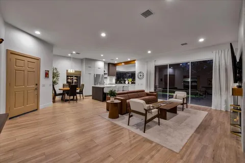 a living room with furniture kitchen view and a large window
