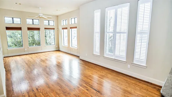 a view of an empty room with a window and wooden floor