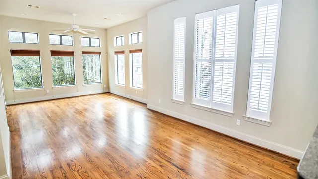 a view of an empty room with a window and wooden floor