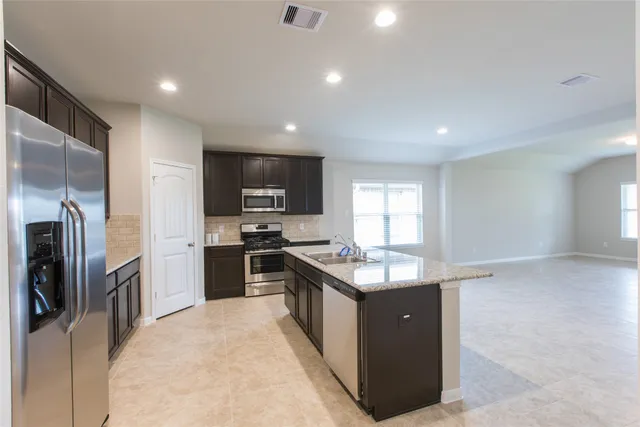 a kitchen with stainless steel appliances granite countertop a sink stove and refrigerator