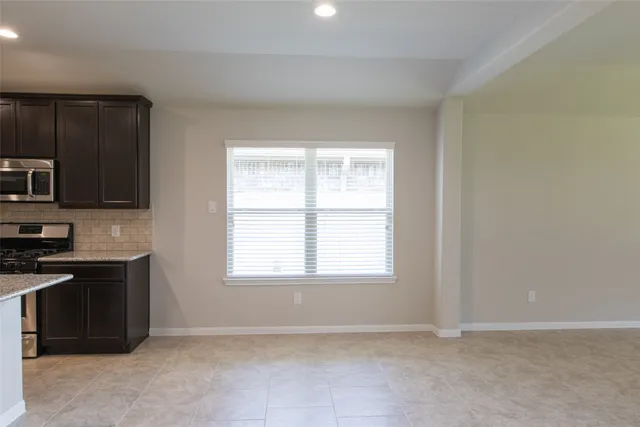 a view of an empty room with a window and a kitchen