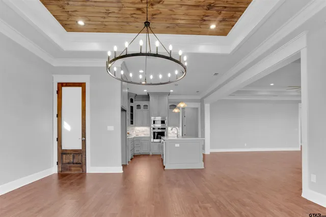 a view of a room with wooden floor gym equipment and chandelier