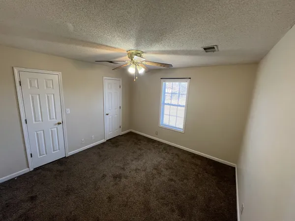 an empty room with windows and fan