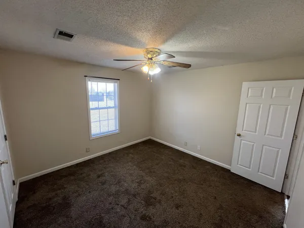 an empty room with windows and fan