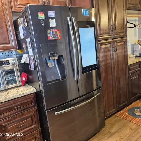 a kitchen with stainless steel appliances granite countertop a refrigerator a sink dishwasher and wooden cabinets with wooden floor