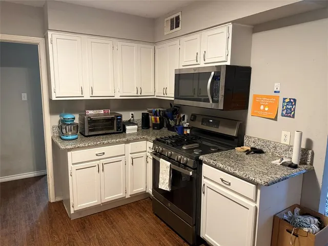 a kitchen with granite countertop cabinets stainless steel appliances and wooden floor